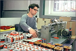 Un opérateur fabricant une bobine Mundorf sur une machine de production